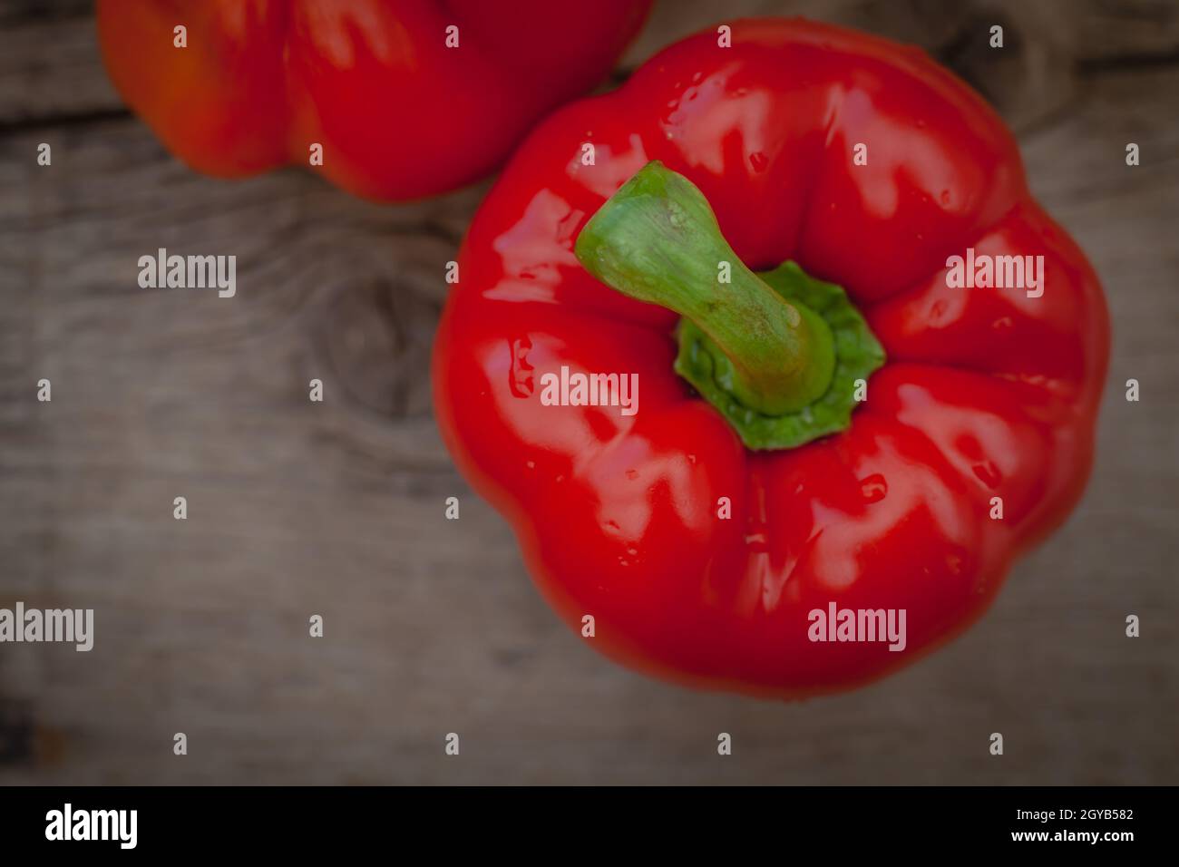 Rote Paprika mit glänzenden Wassertropfen auf rustikalem Holzhintergrund Stockfoto