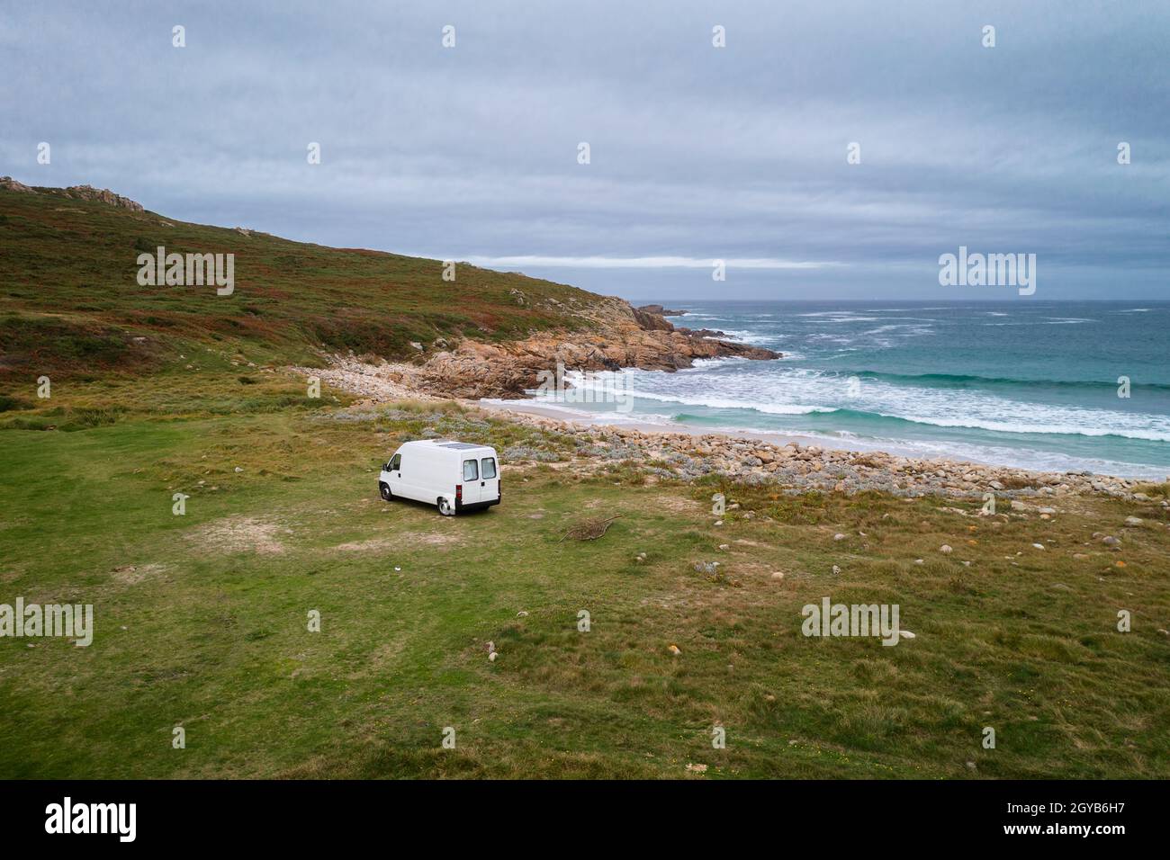 Drohne Luftaufnahme eines Wohnwagens an einem wilden Strand mit grüner Landschaft in Galicien, Spanien Stockfoto