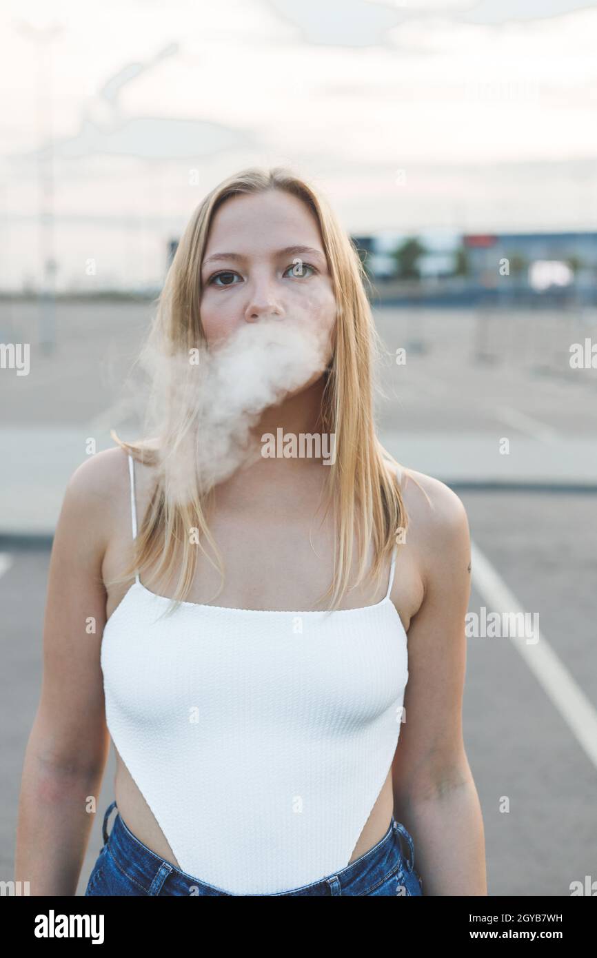 Blonde Frau in der Stadt mit elektronischer Zigarre bereit für vaping Stockfoto