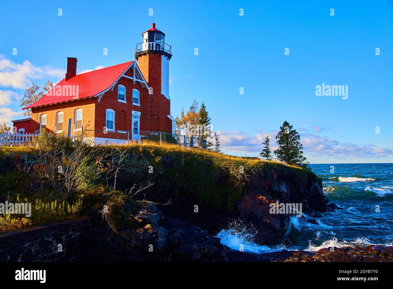 Leuchtturm am Eagle Harbour mit ein paar Bäumen und turbulentem Wasser Stockfoto