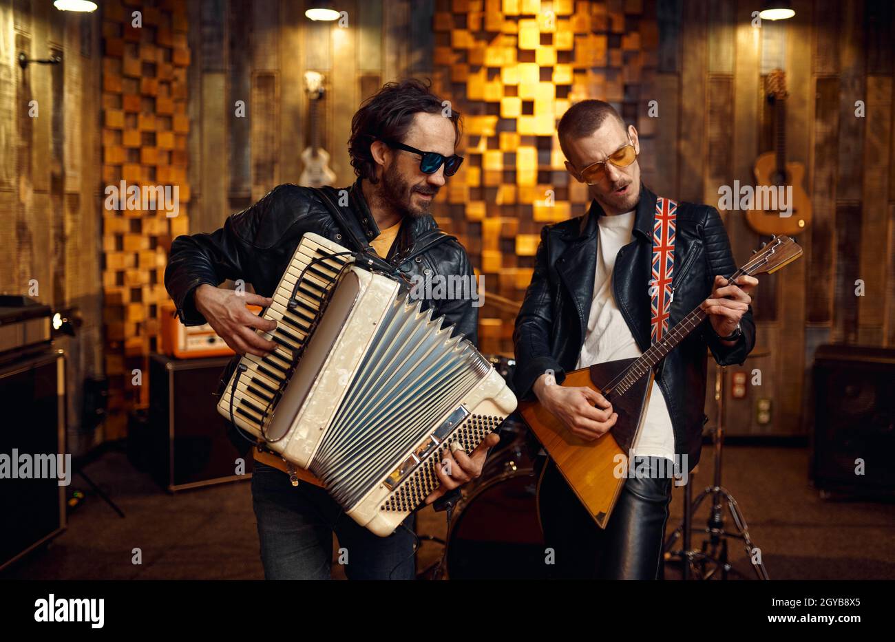Zwei brutale Künstler mit Akkordeon und Balalaika, Musik auf der Bühne. Rockband Auftritt oder Wiederholung in der Garage, Mann mit Musikinstrument Stockfoto