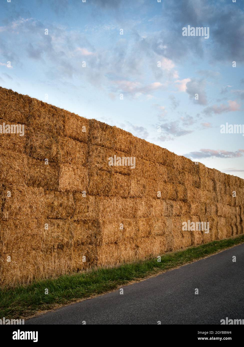 Heuballen stapelten sich auf einem Feld gegen den blauen Himmel mit Wolken Stockfoto