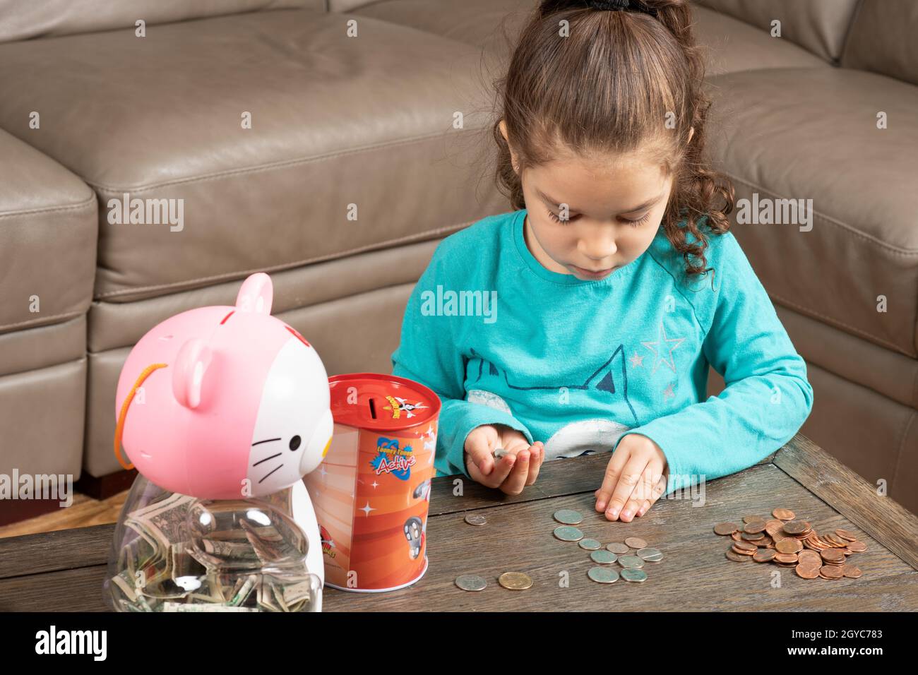 Fünf Jahre altes Mädchen zu Hause, sortiert und zählt Münzen Stockfoto