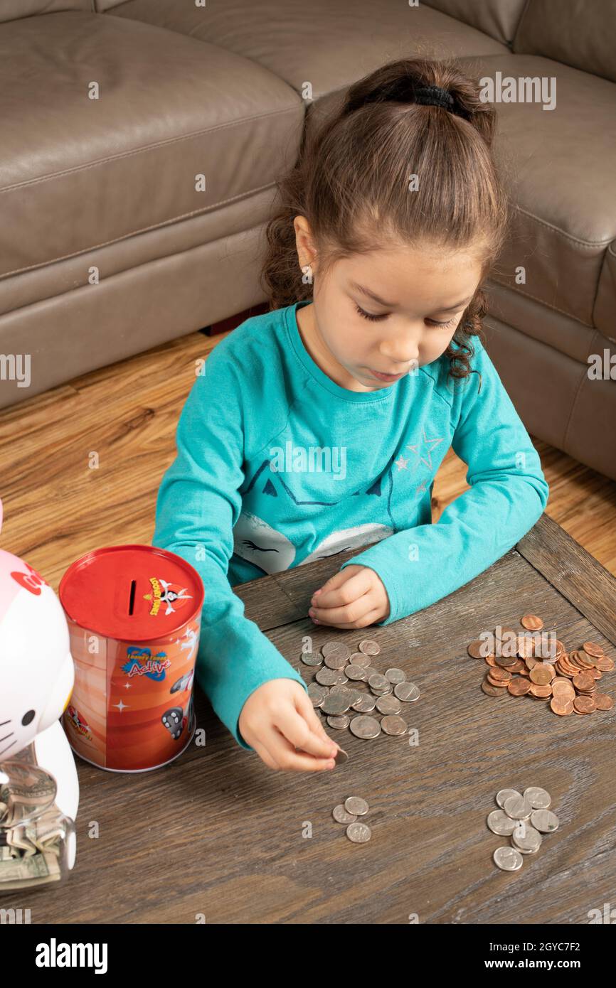 Fünf Jahre altes Mädchen zu Hause, sortiert und zählt Münzen Stockfoto