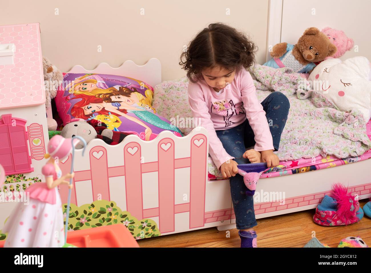 3-jähriges Mädchen zu Hause im Schlafzimmer selbst Pflege Dressing selbstziehend auf Socke Stockfoto