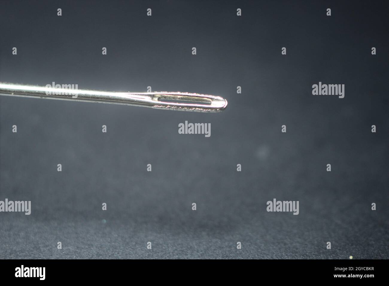 Makroaufnahme einer Nähnadel. Kleine Nadel mit leerer Öse isoliert auf schwarzem Hintergrund. Stockfoto