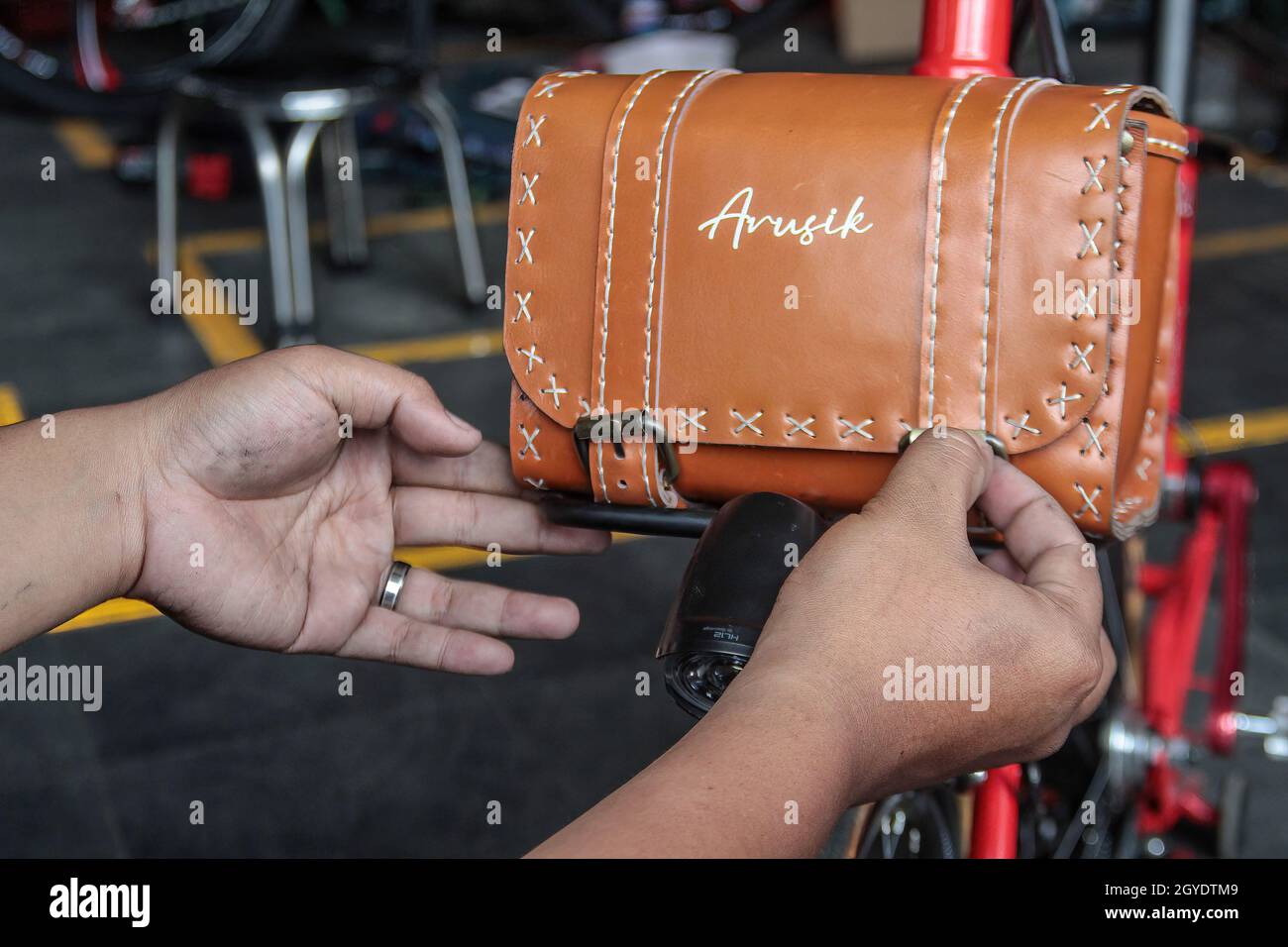 Bandung, Indonesien. Oktober 2021. Ein Mechaniker sah in der Werkstatt von Arusik Bikes in Bandung, wie er ein Batteriefach an einem Faltfahrrad installierte, das in ein Elektrofahrrad umgewandelt wird. Die Standard-Fahrrad-Innovation, die mit Strom modifiziert wird, basiert auf einem zusätzlichen Dynamo am Rad mit einem „Pedal Assist“- und „Gas-Gaspedal“-System, das bis zu 70 Kilometer hält. Die Custom-Akku-Power 'Arusik Bike' reicht von 250 bis 300 Watt bei einer Akkuladezeit von 4 Stunden von Null bis voll. Kredit: SOPA Images Limited/Alamy Live Nachrichten Stockfoto