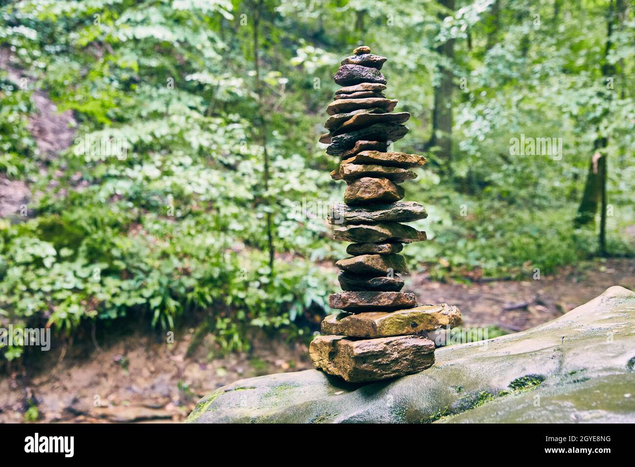 Hoher Steinhaufen auf gedämpftem grünem Waldgrund Stockfoto