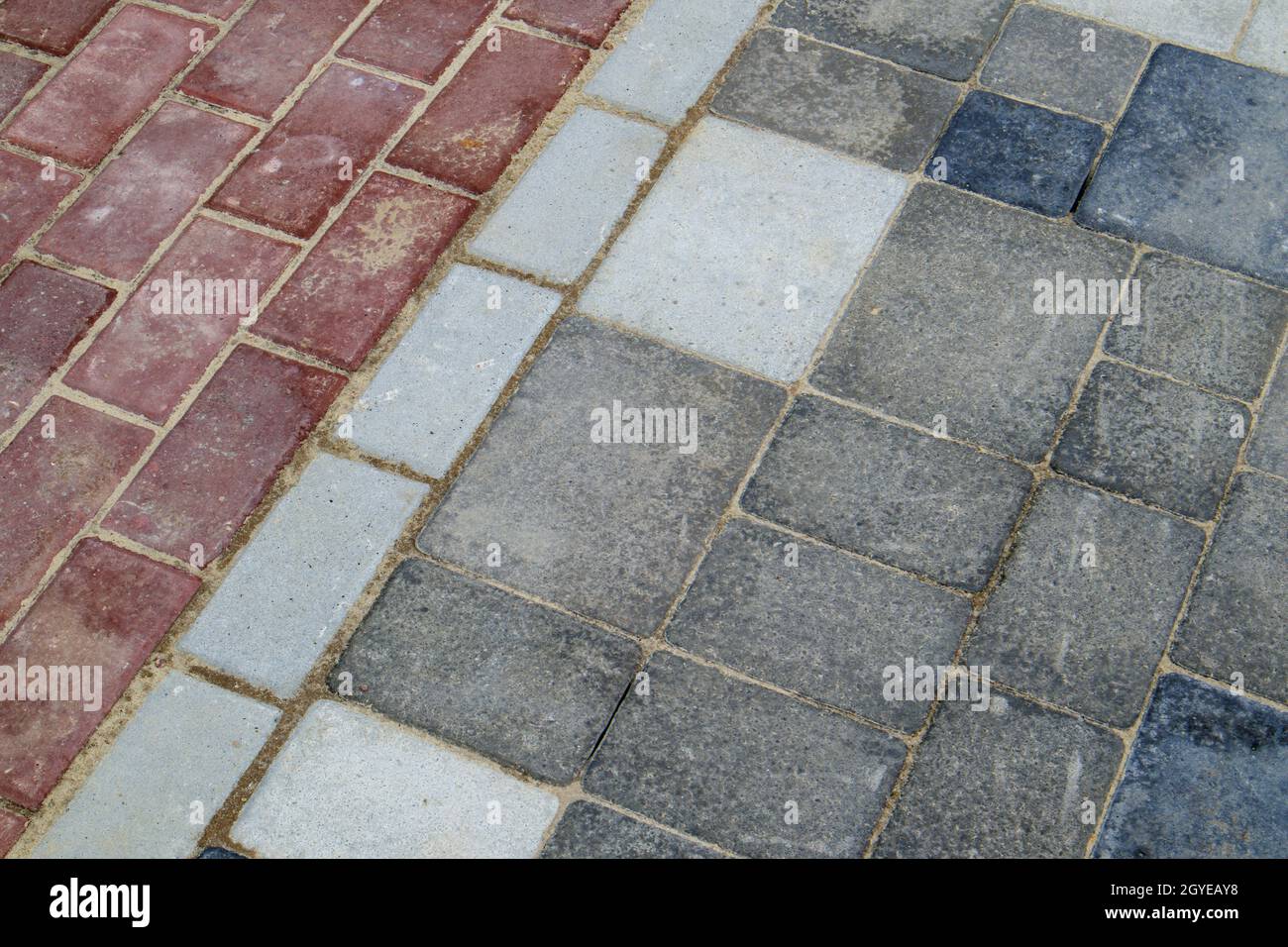 Beton oder gepflasterte, neu verlegte graue und rote Pflasterplatten oder Steine für Fußböden oder Gehwege. Betonpflaster Platten im Hinterhof oder Straßenpflaster. Garten Stockfoto