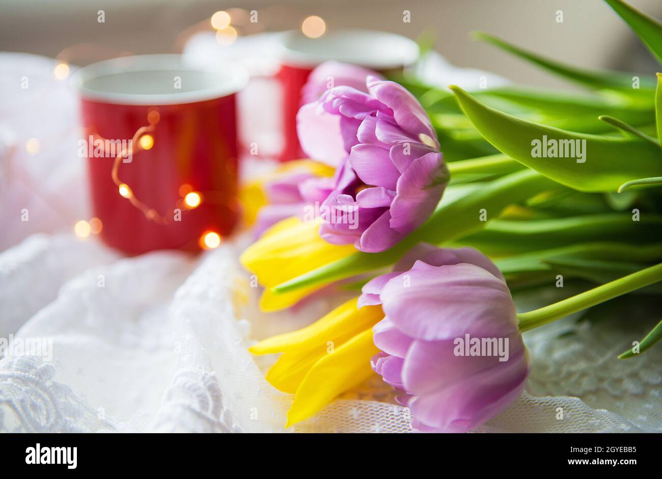 Schöner Morgen, zwei Tassen Kaffee und ein Bouquet von hellen Tulpen. Stockfoto