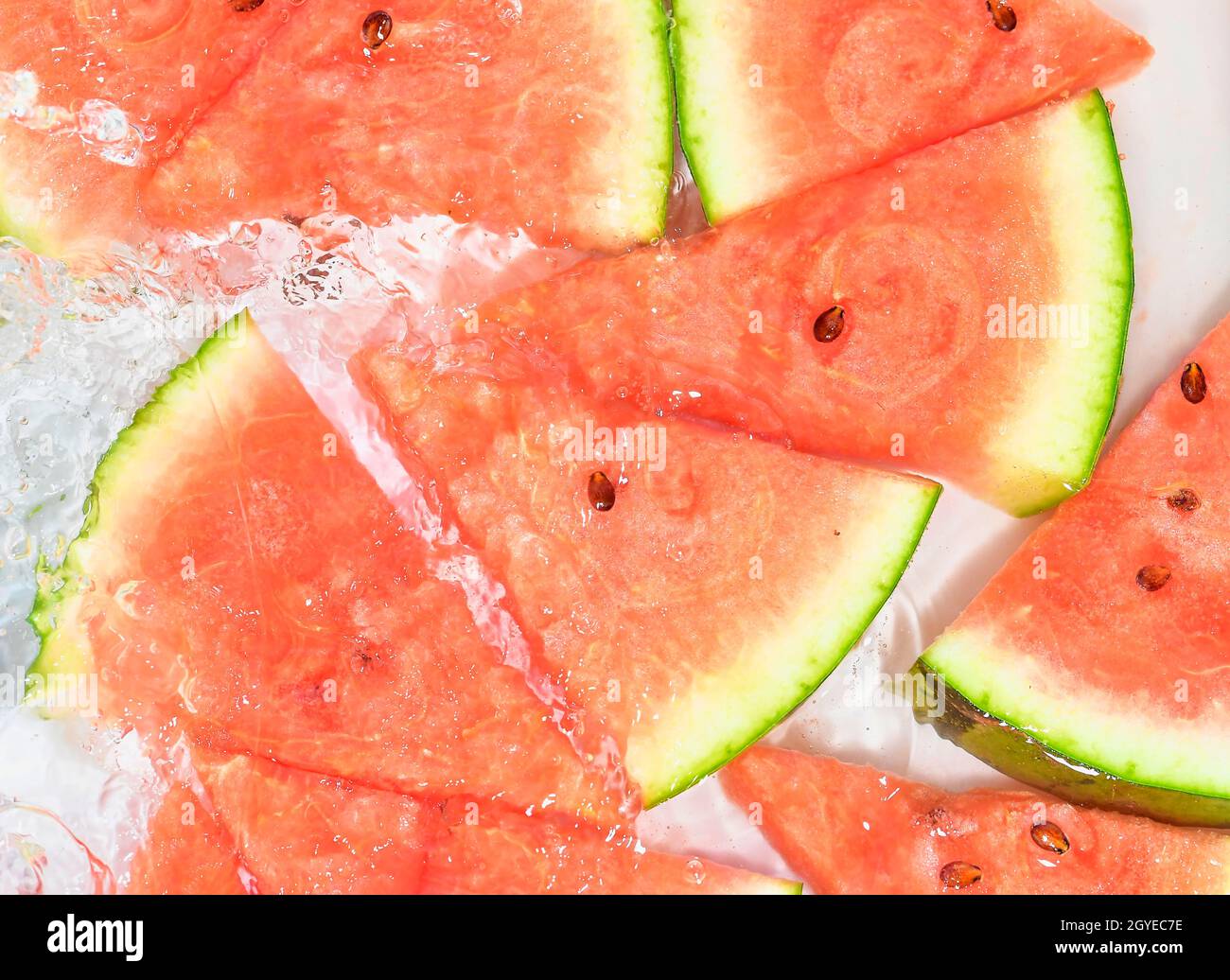 Melonenscheiben im Wasser auf weißem Hintergrund. Melone close-up in Flüssigkeit mit Blasen. Scheiben rote reife Melone in Wasser. Makrobild von Früchten im Wasser Stockfoto