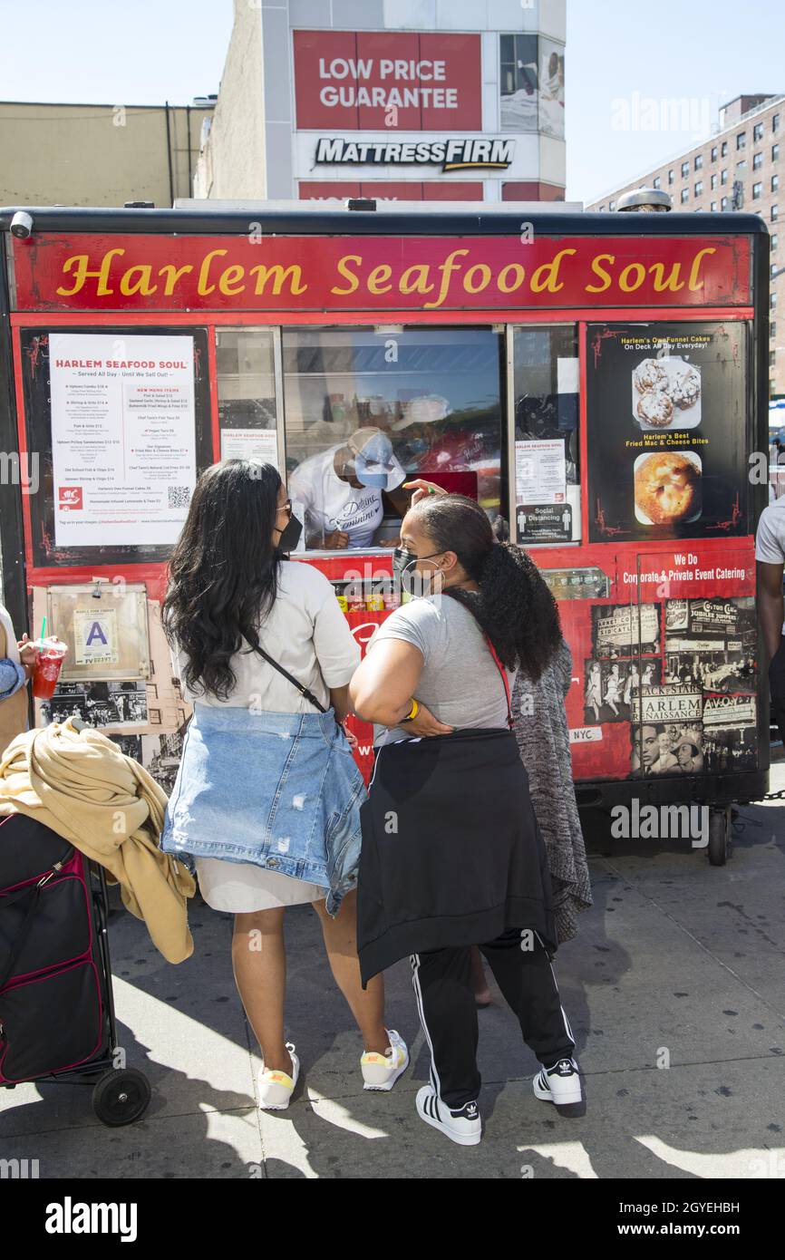 Die Menschen kaufen Meeresfrüchte bei einem Straßenhändler in der 125th Street in Harlem, New York City. Stockfoto