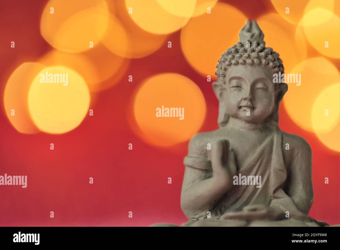 Buddha auf rotem Hintergrund mit goldenem Bokeh.Meditation und Entspannung.Buddhismus Religion Hintergrund. Stockfoto