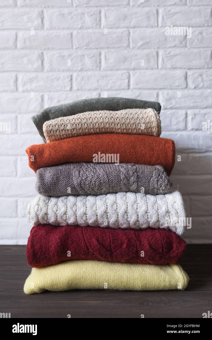 Kuschelige Pullover in Herbstfarben auf braunem Holzhintergrund. Platz für Text. Stockfoto