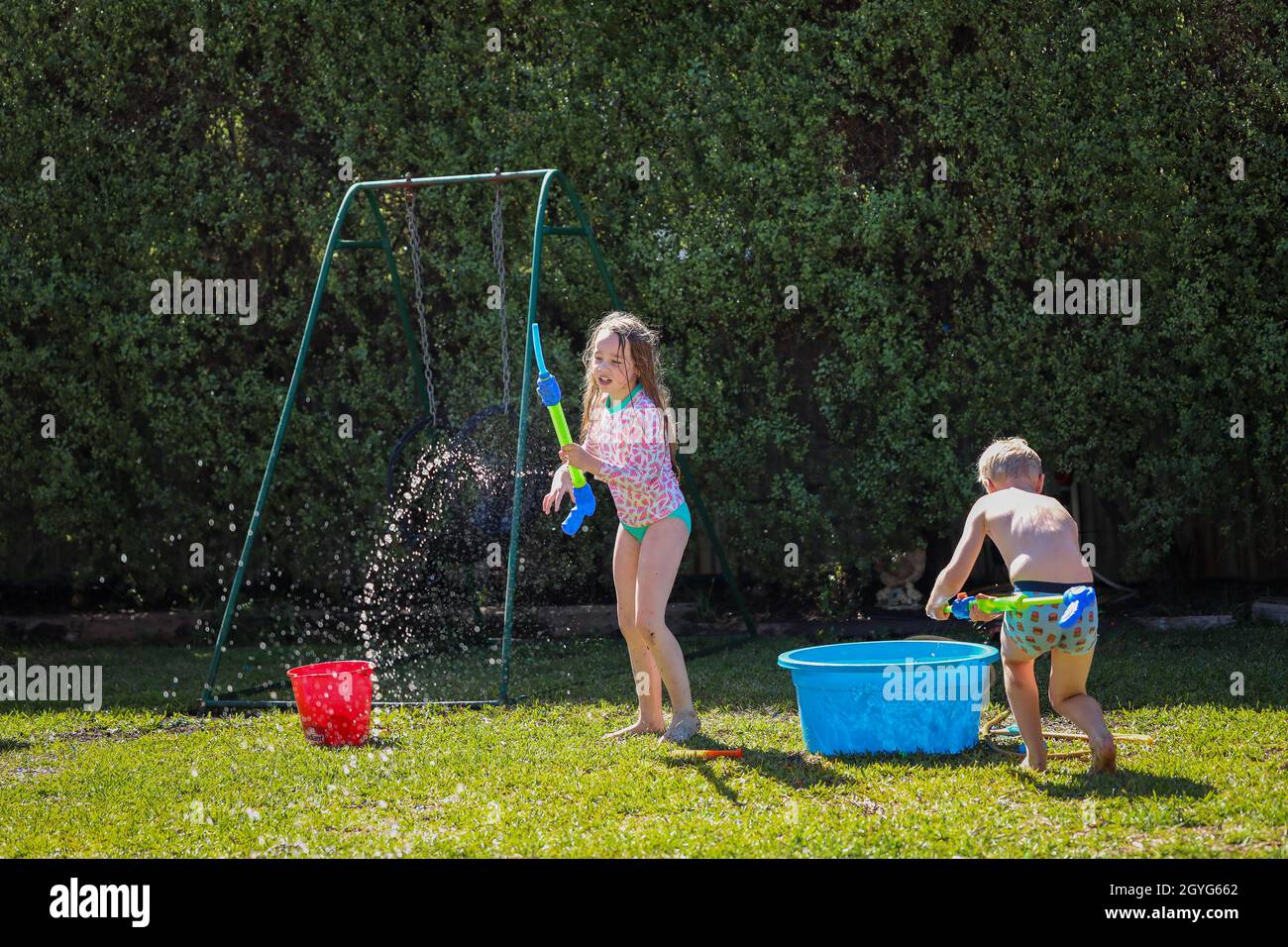 Australische Kinder genießen im Sommer Wasserschlacht im Garten Stockfoto