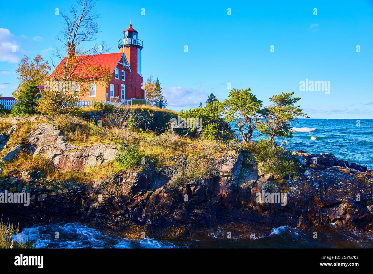 Leuchtturm am Eagle Harbor mit felsigen Klippen in vielen Farben und einem turbulenten Meer aus Wasser Stockfoto