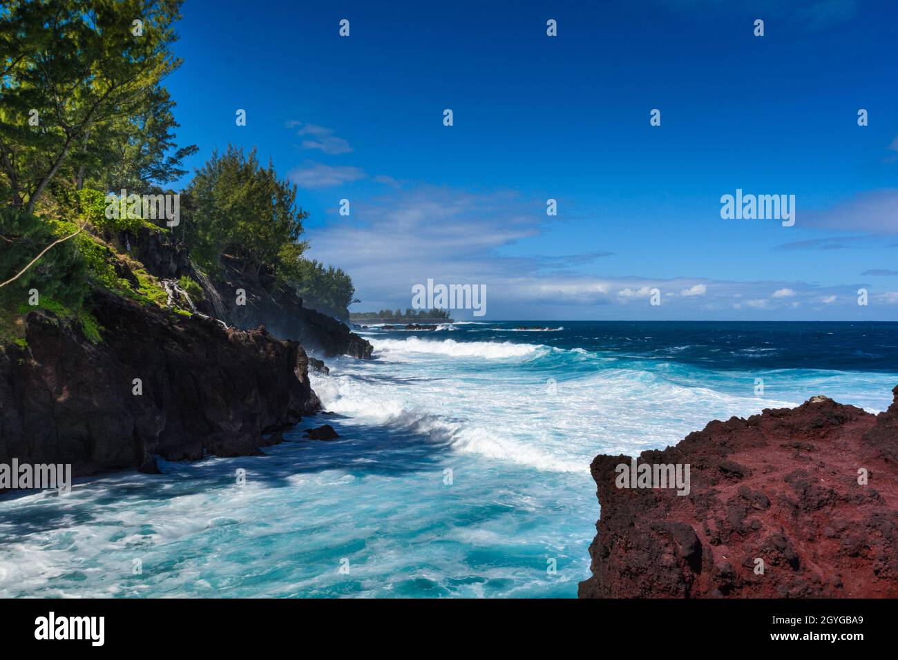 Wellen und vulkanisches Gestein an der Südküste von Reunion Island an einem sonnigen Tag Stockfoto