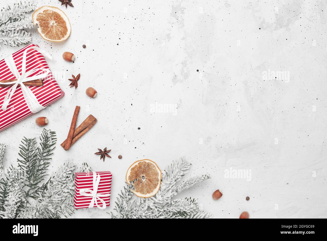 Weihnachten flach Lay Draufsicht auf weiß grauen Beton Hintergrund Tisch mit Geschenk roten Geschenkboxen, Dekorationen, Zimt-Sticks, Haselnuss, getrocknete Orange Stockfoto