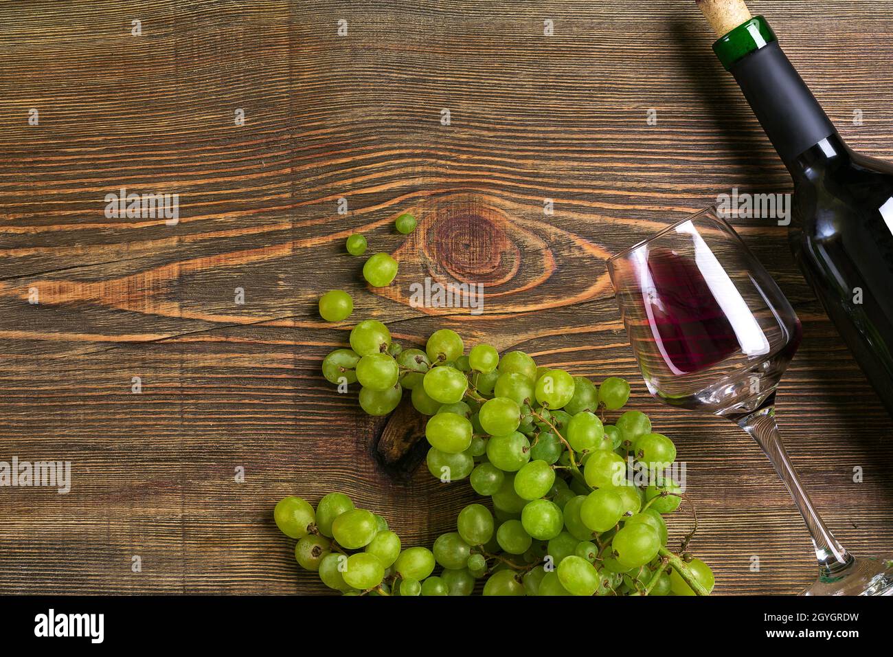 Gläser, Flasche Rotwein und Traube auf einem Holztisch Stockfoto