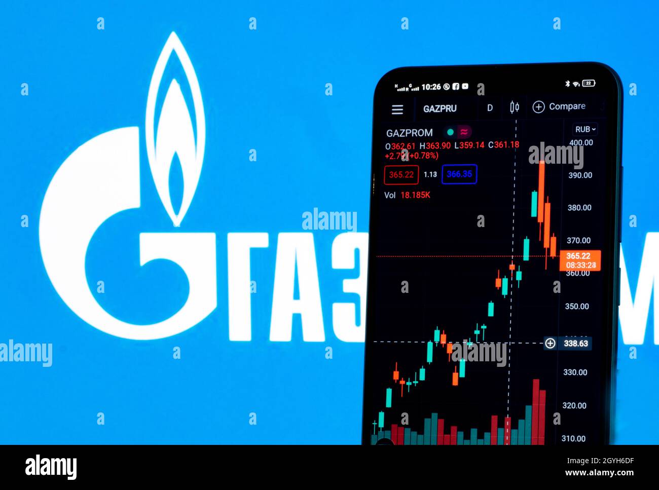 In dieser Abbildung werden die Börseninformationen von Gazprom auf einem Smartphone angezeigt, während das Logo von Gazprom als Hintergrund angezeigt wird Stockfoto