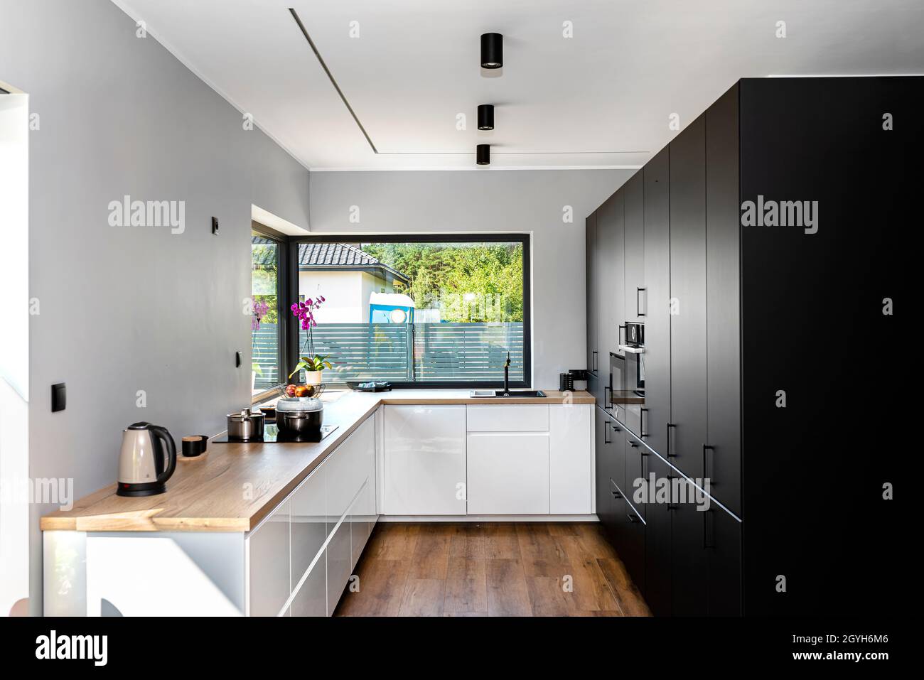 Eine moderne Küche mit weißen und schwarzen Fronten und einem großen  Eckfenster, Vinylplatten auf dem Boden Stockfotografie - Alamy