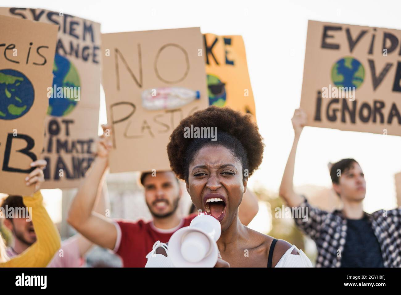 Junge Gruppe von Demonstranten, die aus verschiedenen Kulturen unterwegs sind und für den Klimawandel kämpfen – Fokus auf afrikanisches Frauengesicht Stockfoto