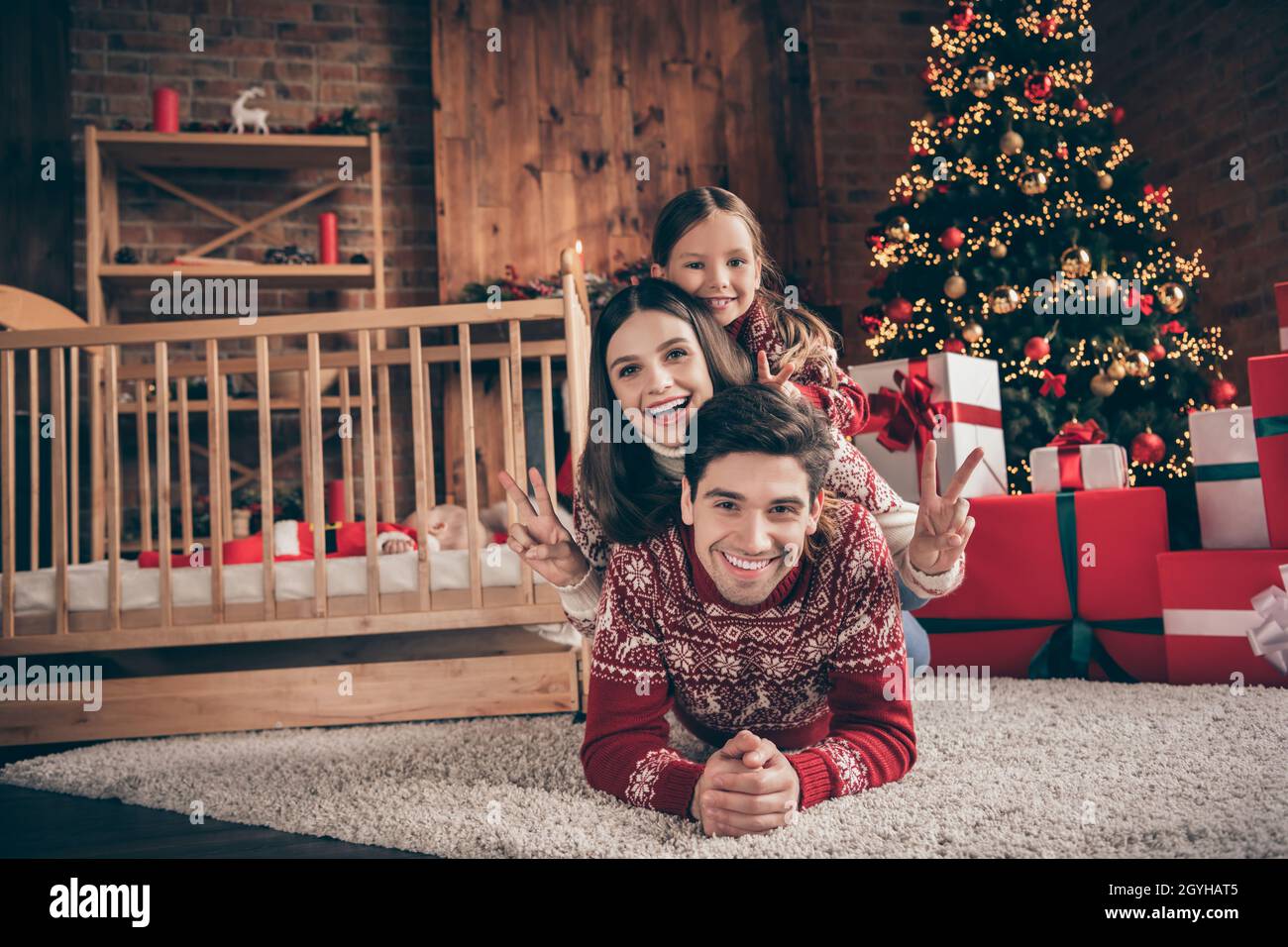 Foto von schönen Familie Mutter Vater Tochter neu geboren Sohn zeigen  V-Zeichen tragen roten Pullover am weihnachtstag im Loft Stockfotografie -  Alamy