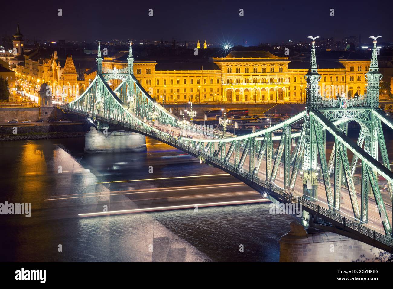 Freiheitsbrücke gegen das Corvinus-Universitätsgebäude in Budapest bei Nacht Stockfoto