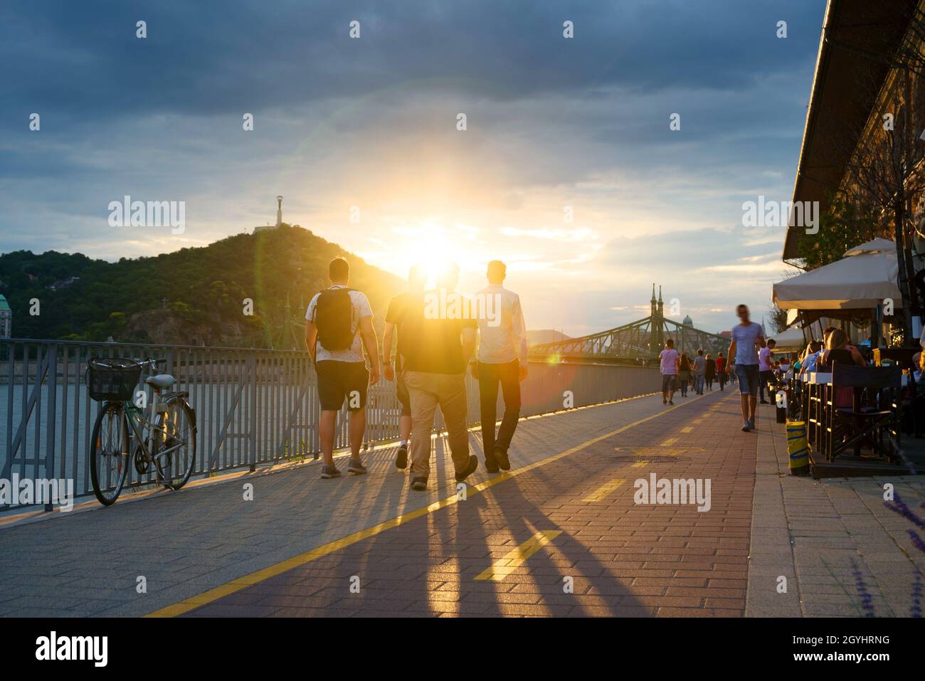 Menschen mit Hintergrundbeleuchtung, die bei Sonnenuntergang entlang der Uferpromenade spazieren Stockfoto