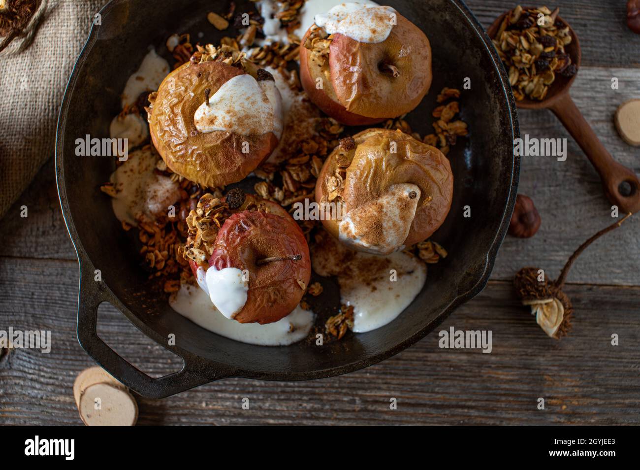 Hausgemachtes Frühstückszerealien mit frisch gebackenen Äpfeln und Müsli mit Zimt und Joghurt. Serviert auf rustikalem Holztisch. Stockfoto