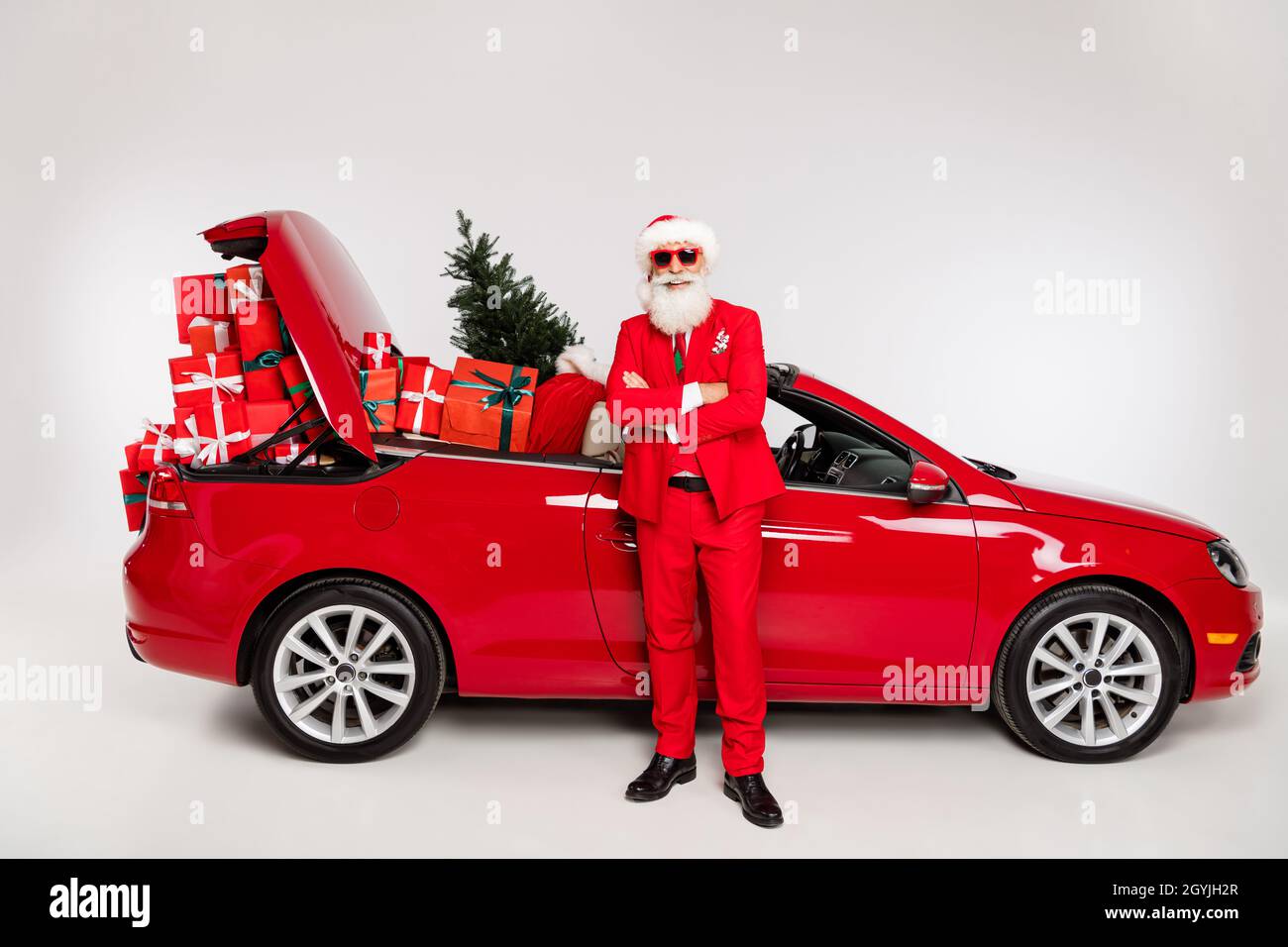 Foto von ziemlich zuversichtlich santa claus Reiten Auto Arme gefaltet liefern präsentiert isoliert weiße Farbe Hintergrund Stockfoto