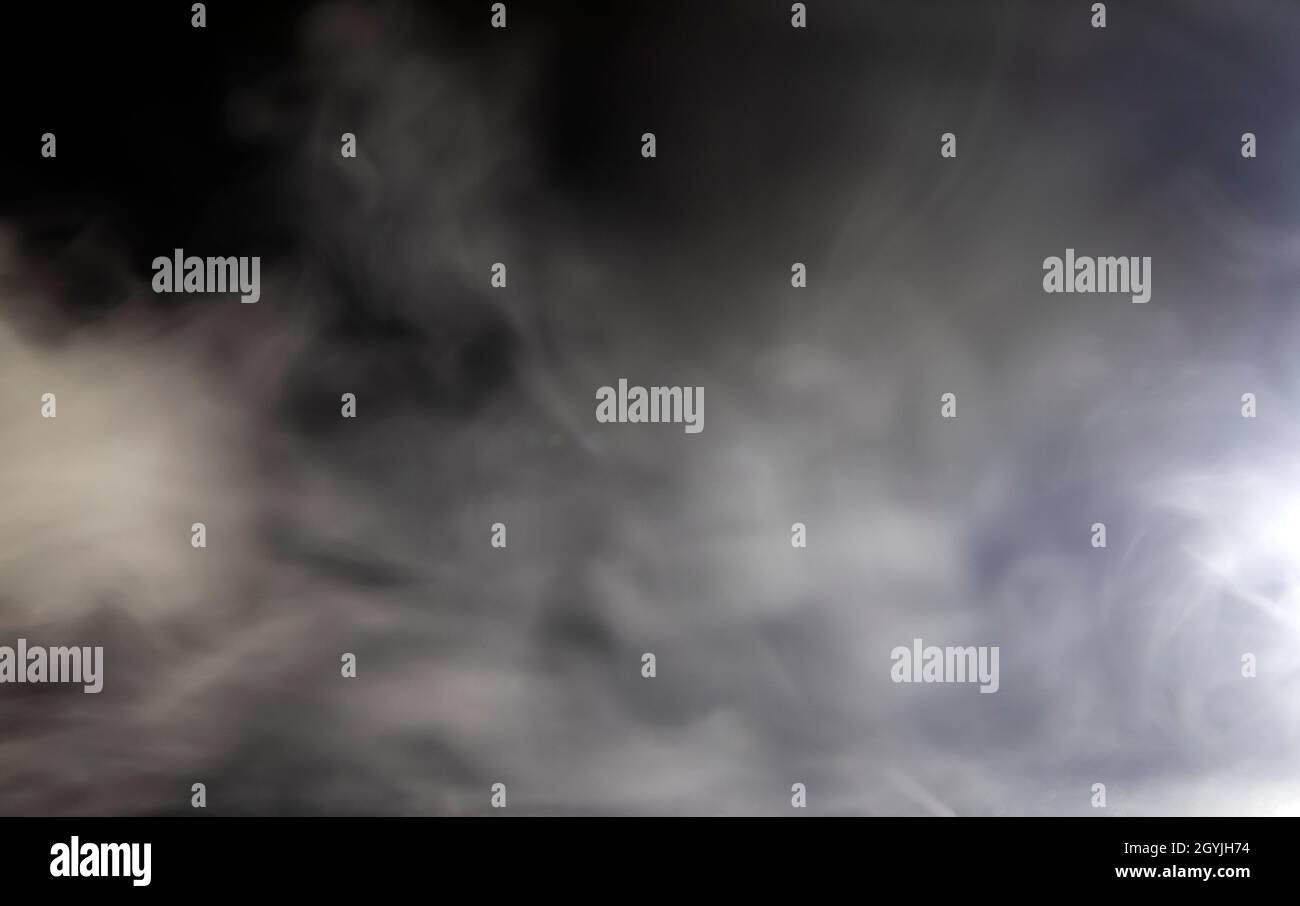 Abstraktes Design aus weißer Wolke auf dunklem Hintergrund. Verschwommene Rauchbewegung. Stockfoto