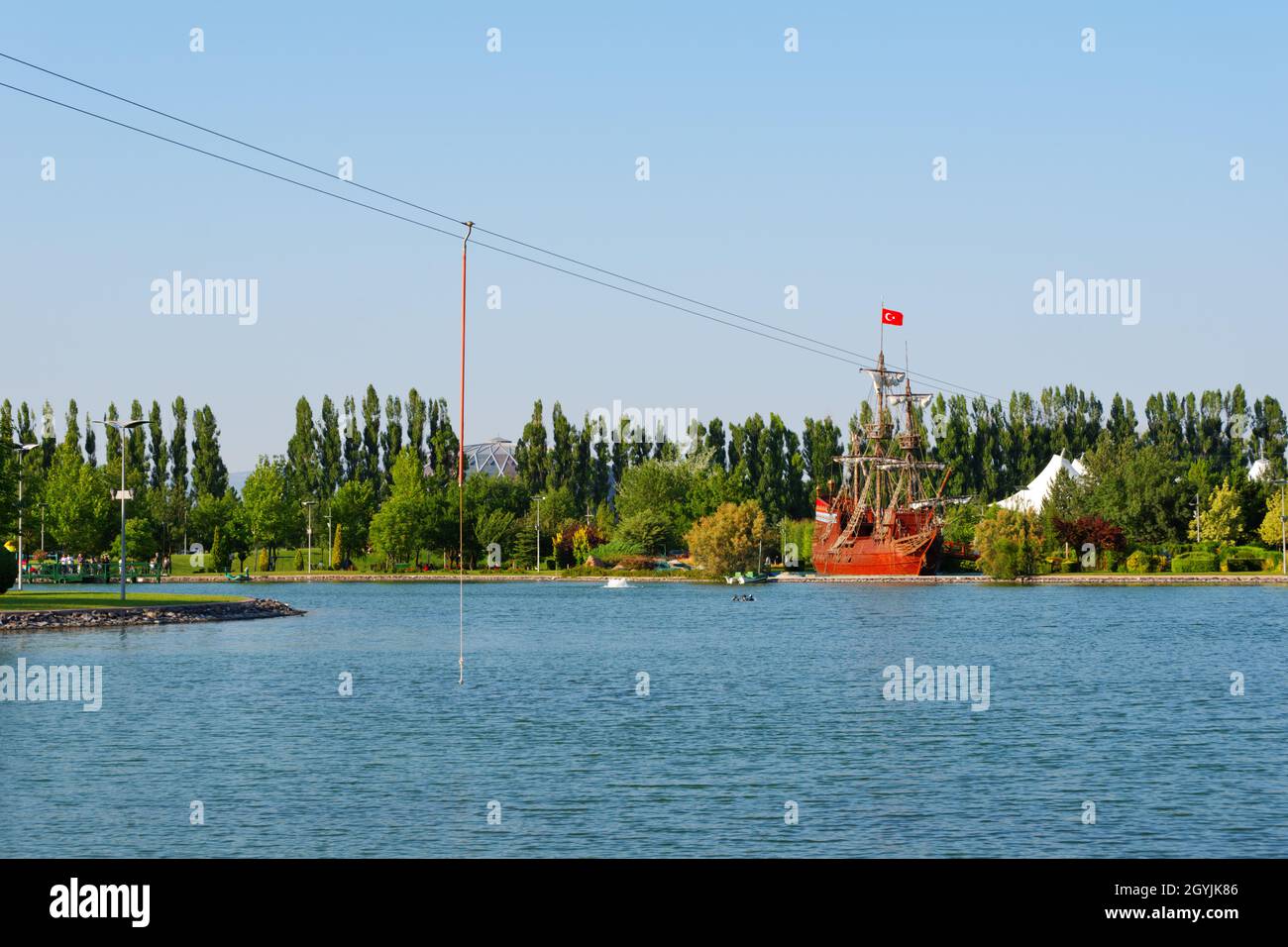 Holzschiff im Retro-Stil am See mit grünen Bäumen im Hintergrund an einem sonnigen Sommertag im Freien Stockfoto