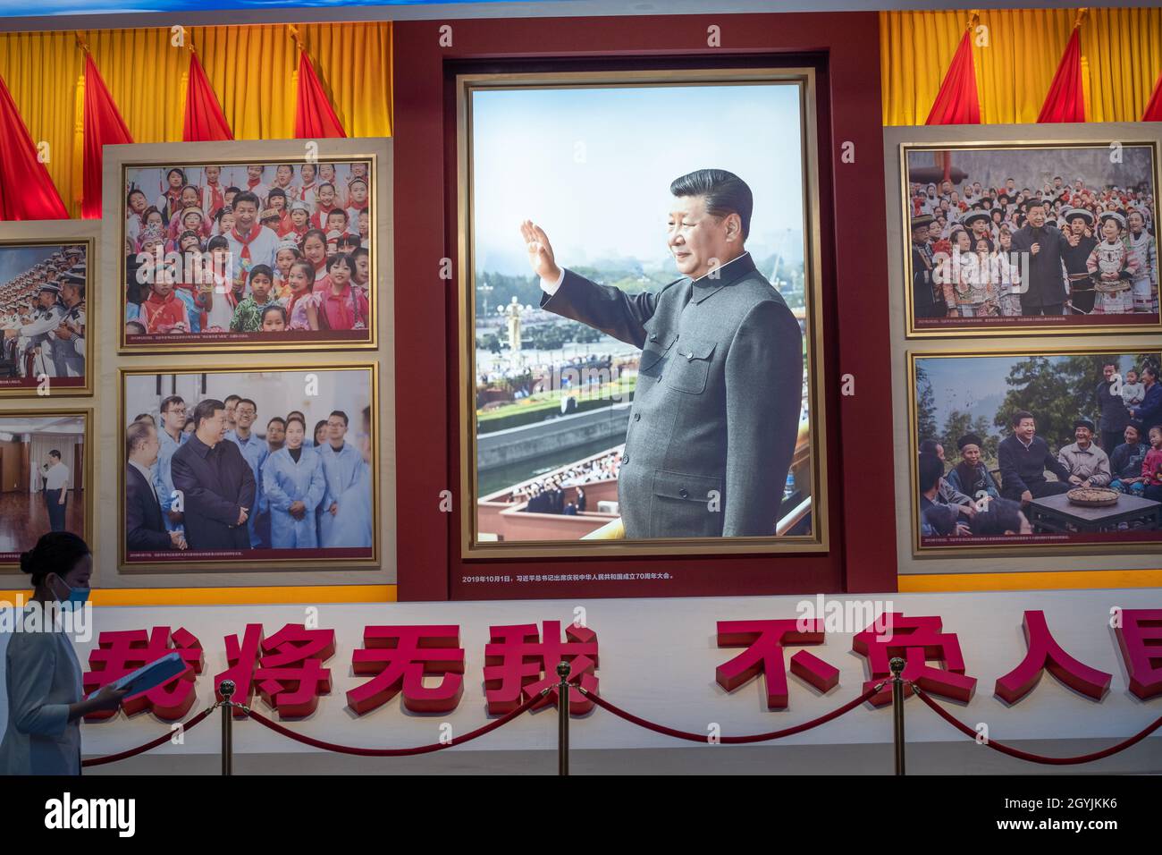 Eine Dame geht an Bildern vorbei, die den chinesischen Präsidenten Xi Jinping im Museum der Kommunistischen Partei Chinas in Peking zeigen. 08-Okt-2021 Stockfoto