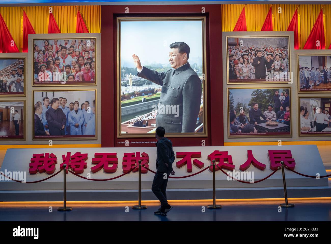 Ein Mann geht an Bildern vorbei, die den chinesischen Präsidenten Xi Jinping im Museum der Kommunistischen Partei Chinas in Peking zeigen. 08-Okt-2021 Stockfoto