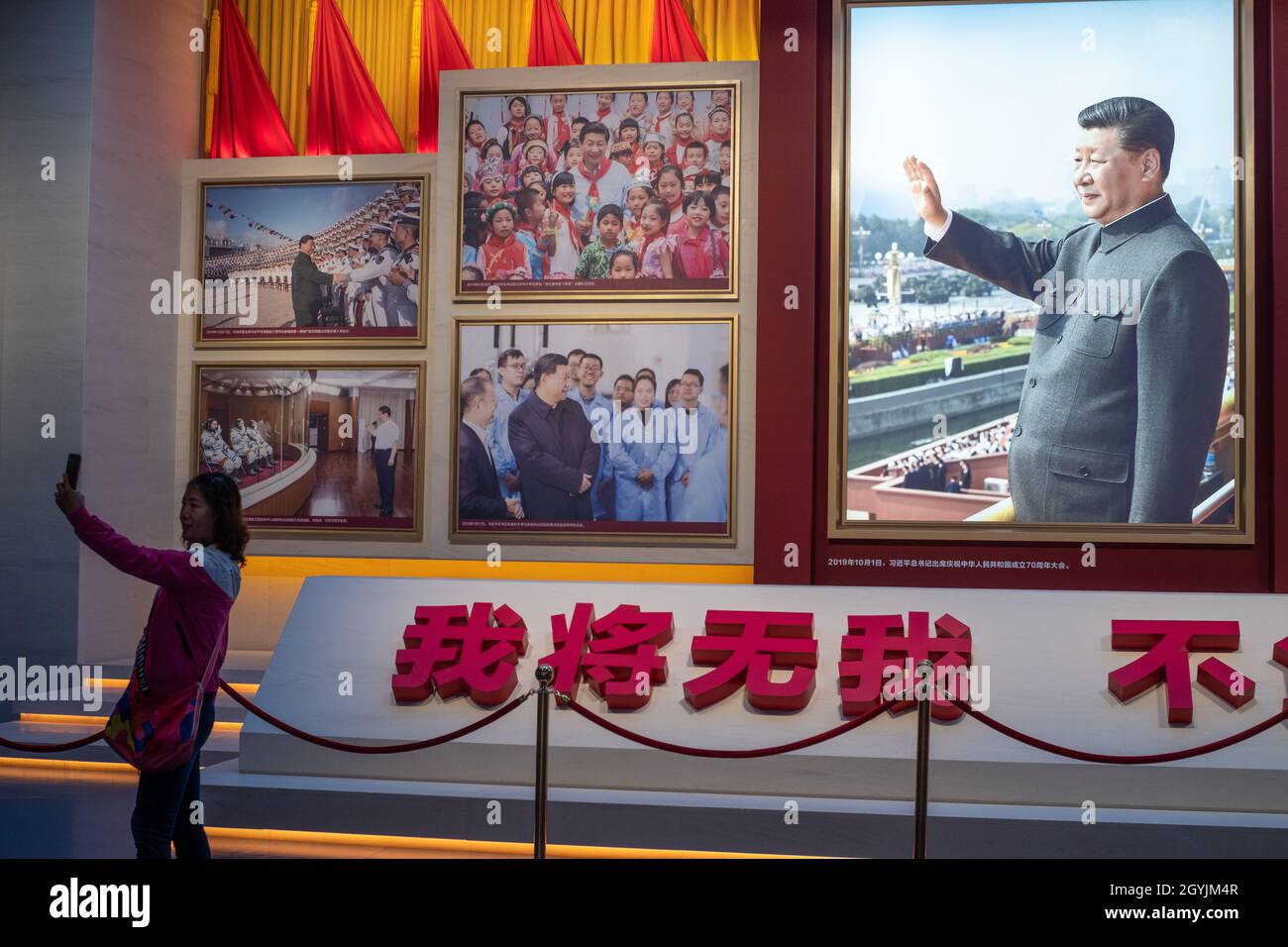 Eine Frau macht ein Selfie vor Bildern, die den chinesischen Präsidenten Xi Jinping im Museum der Kommunistischen Partei Chinas in Peking zeigen. 08-Okt-2021 Stockfoto