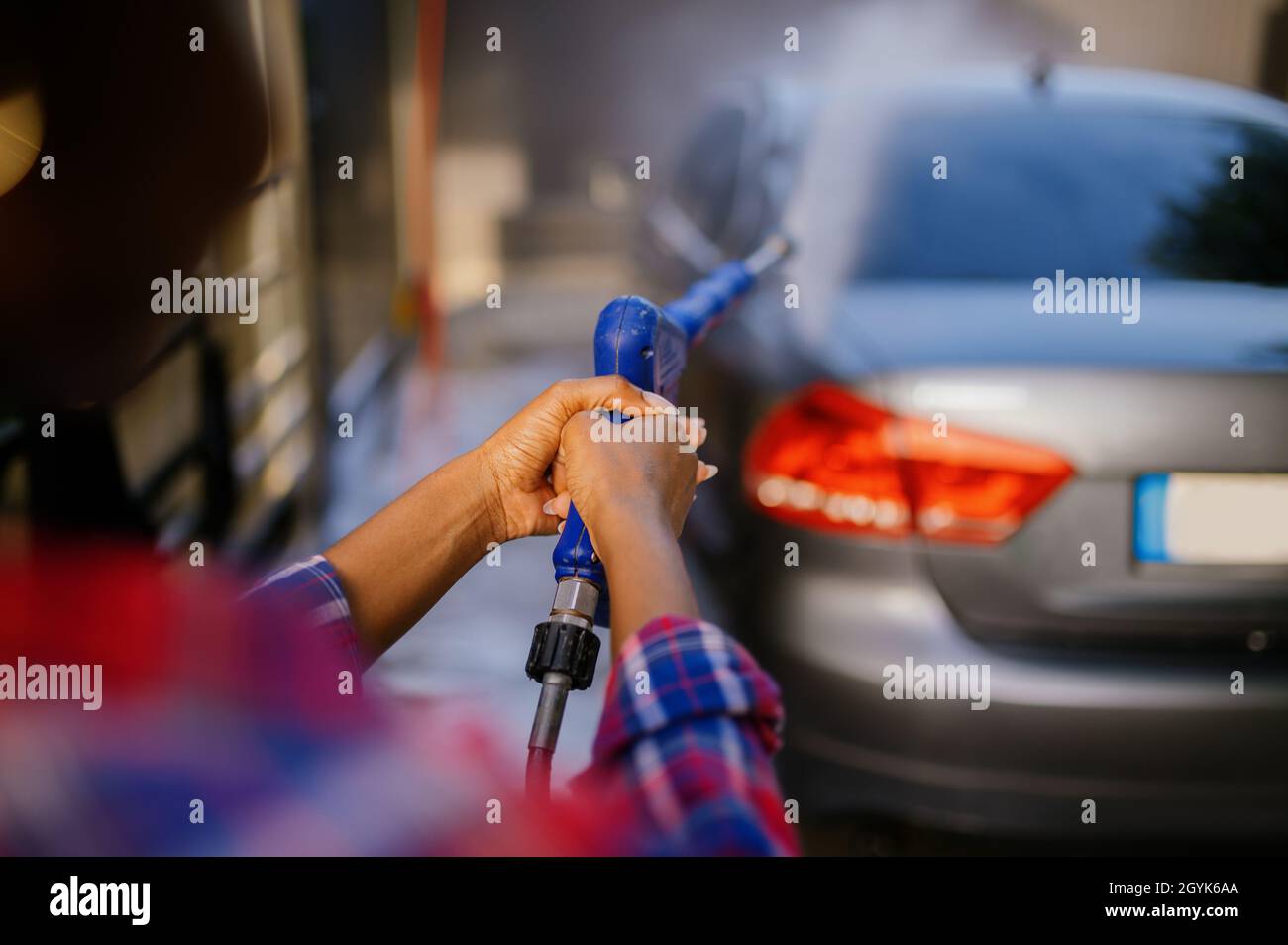 Frau mit Hochdruckwasserkanone, Autowäsche Stockfoto