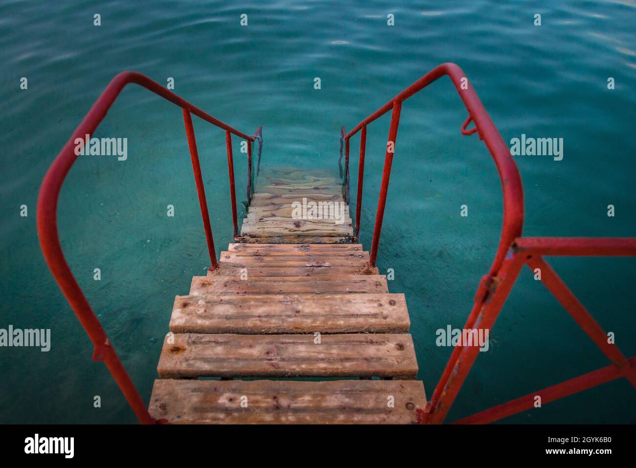Hoch anwinklige Aufnahme einer hölzernen Treppe mit roten Geländern, die zum Wasser führen Stockfoto