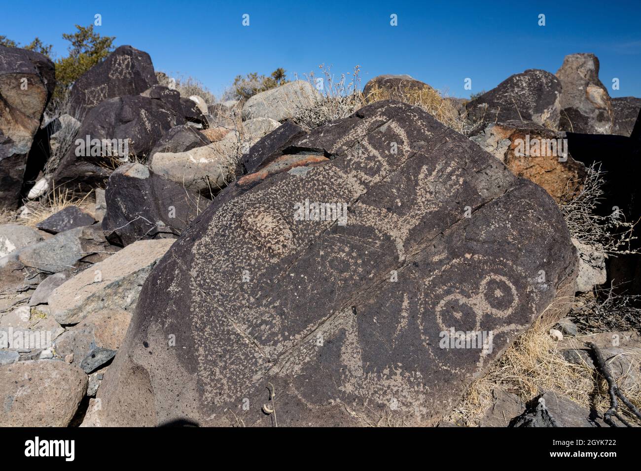 Anthropomorphe Figuren, die auf einem Basaltsteinblock in der Petroglyph-Stätte Three-Flues, New Mexico, geschnitzt wurden. Stockfoto