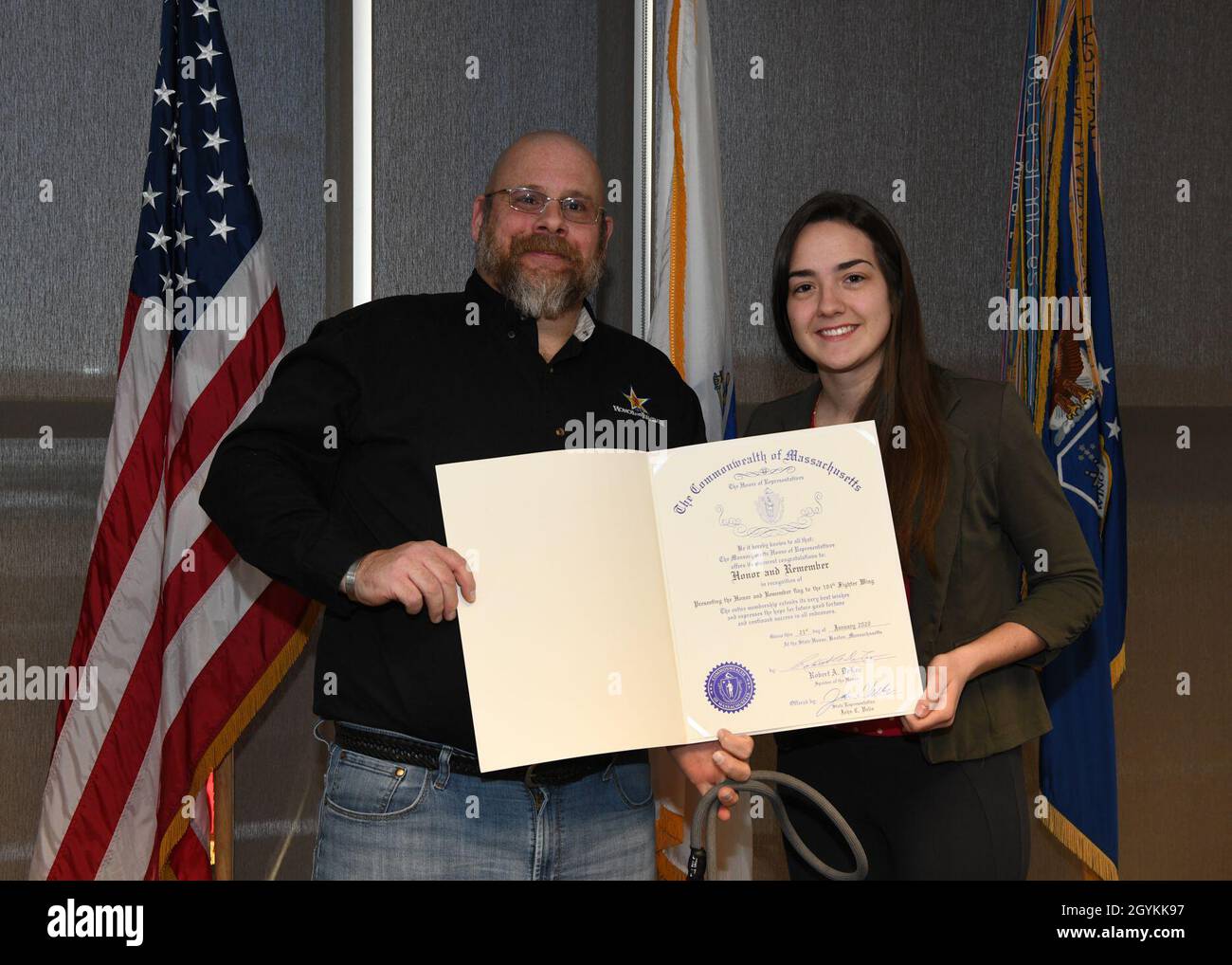 Brian Miller, der Leiter des Kapitels von Honor and Remember in Massachusetts, überreichte Col. Peter T. Green III, dem Befehlshaber des 104. Kampfflügels, eine Ehrenflagge. Chiara McNally, gesetzgebende Berentin des Rep. John Velis, überreichte Miller eine Dankungsurkunde des Repräsentantenhauses von Massachusetts. Honor and Remember erkennt das Opfer gefallener Dienstmitglieder an und tröstet ihre Familien. (US Air National Guard Fotos von Meister Sgt. Lindsey Sarah Watson-Kirwin) Stockfoto