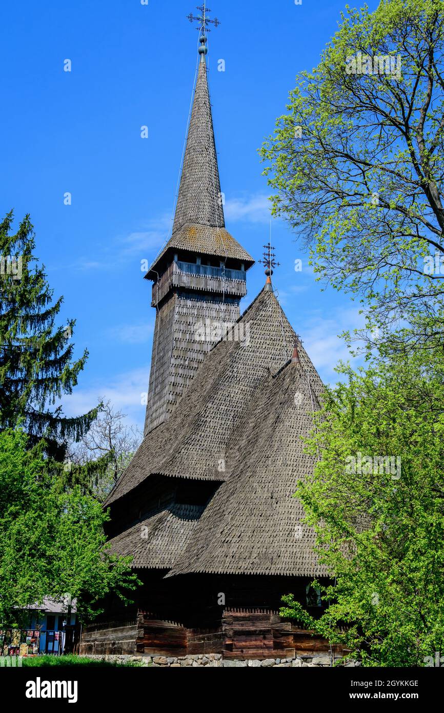 Bukarest, Rumänien - 25. April 2021: Alte traditionelle rumänische Kirche umgeben von vielen alten Bäumen und grünem Gras im Dimitrie Gusti National Village M Stockfoto