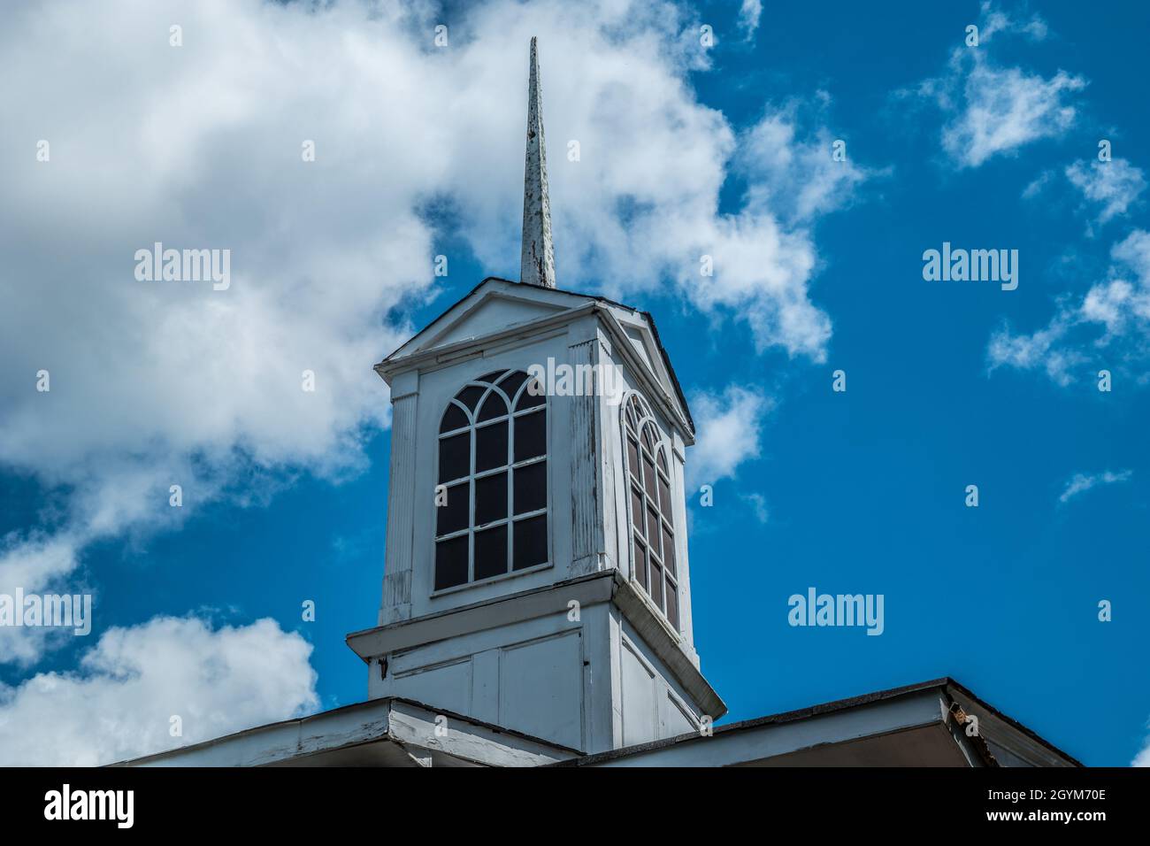 Ein Kirchturm auf dem Dach, der repariert werden muss, mit abblätternder Farbe, die rissig und verfaultes Holz auf einer alten Landkirche war Stockfoto
