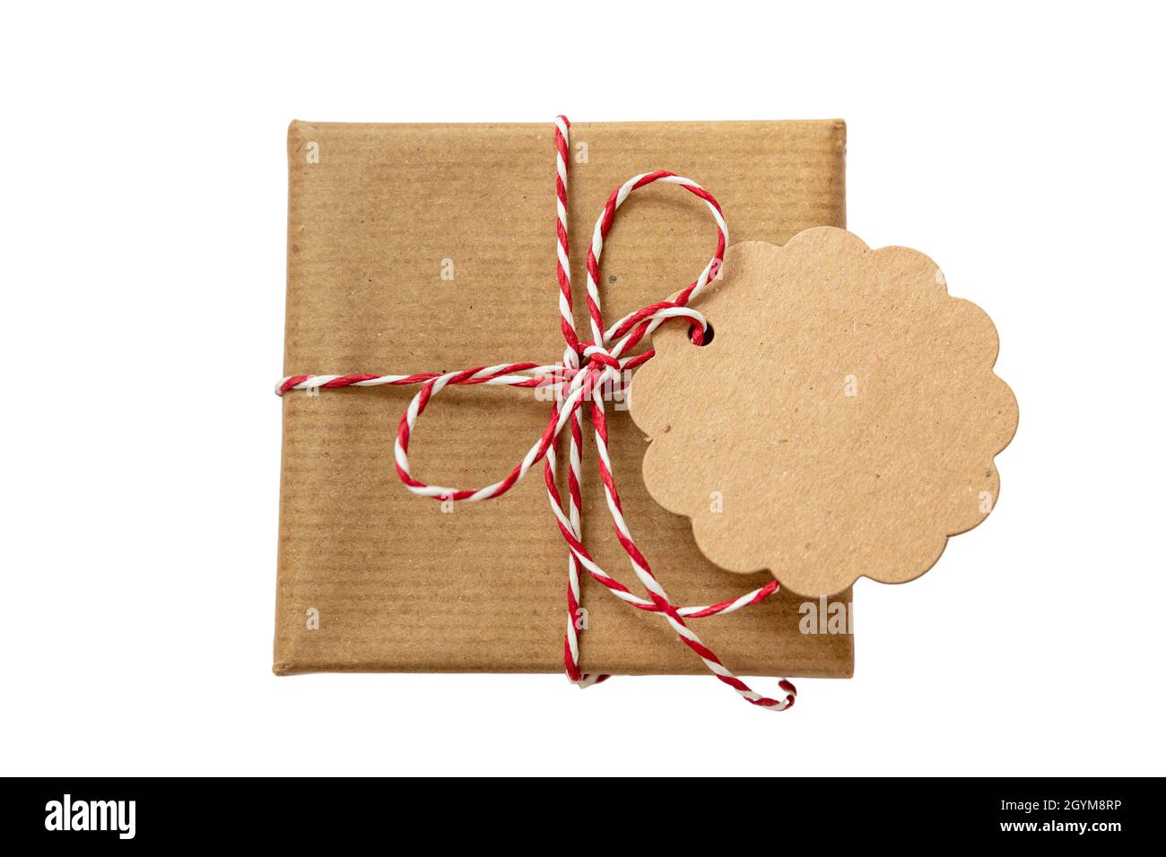 Weihnachtsgeschenkbox mit unbeschriftete runde Note Karte, braunes Kraftpapier Urlaub Geschenk mit rot weiß gestreiften String gebunden Bogen isoliert Ausschnitt auf weißem Rücken Stockfoto