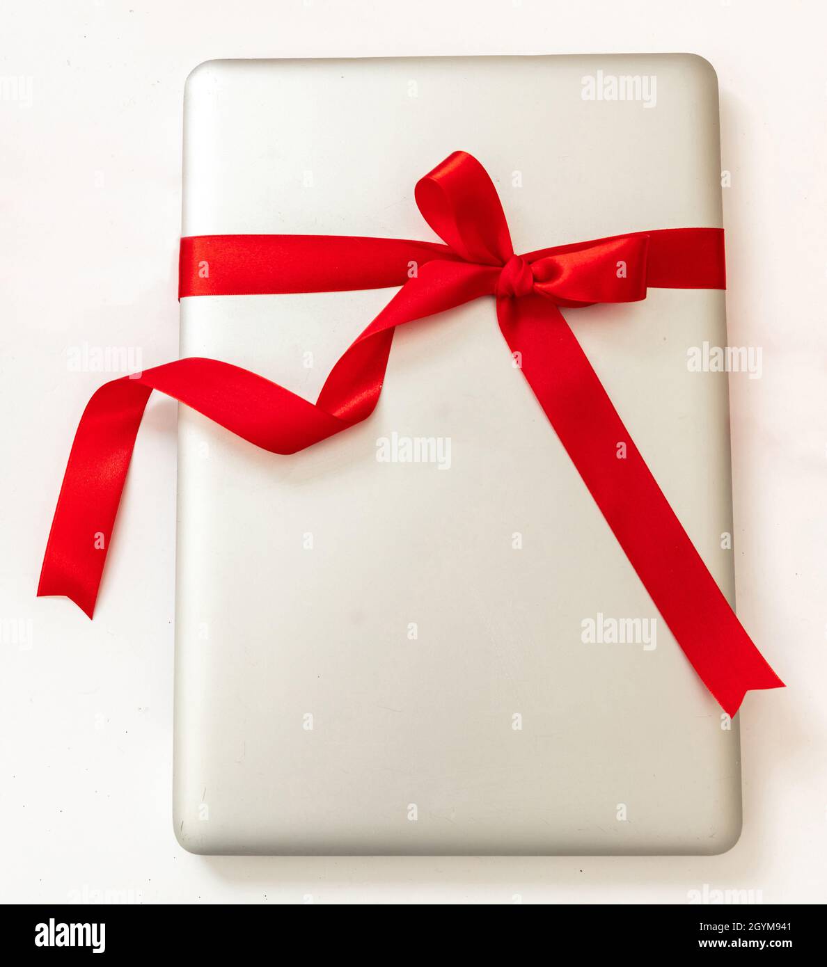 Laptop-Computer mit rotem Band Schleife, Digital-Gerät Weihnachtsgeschenk isoliert auf weißem Hintergrund. Valentinstag, Weihnachtsgeschenk, Draufsicht. Stockfoto