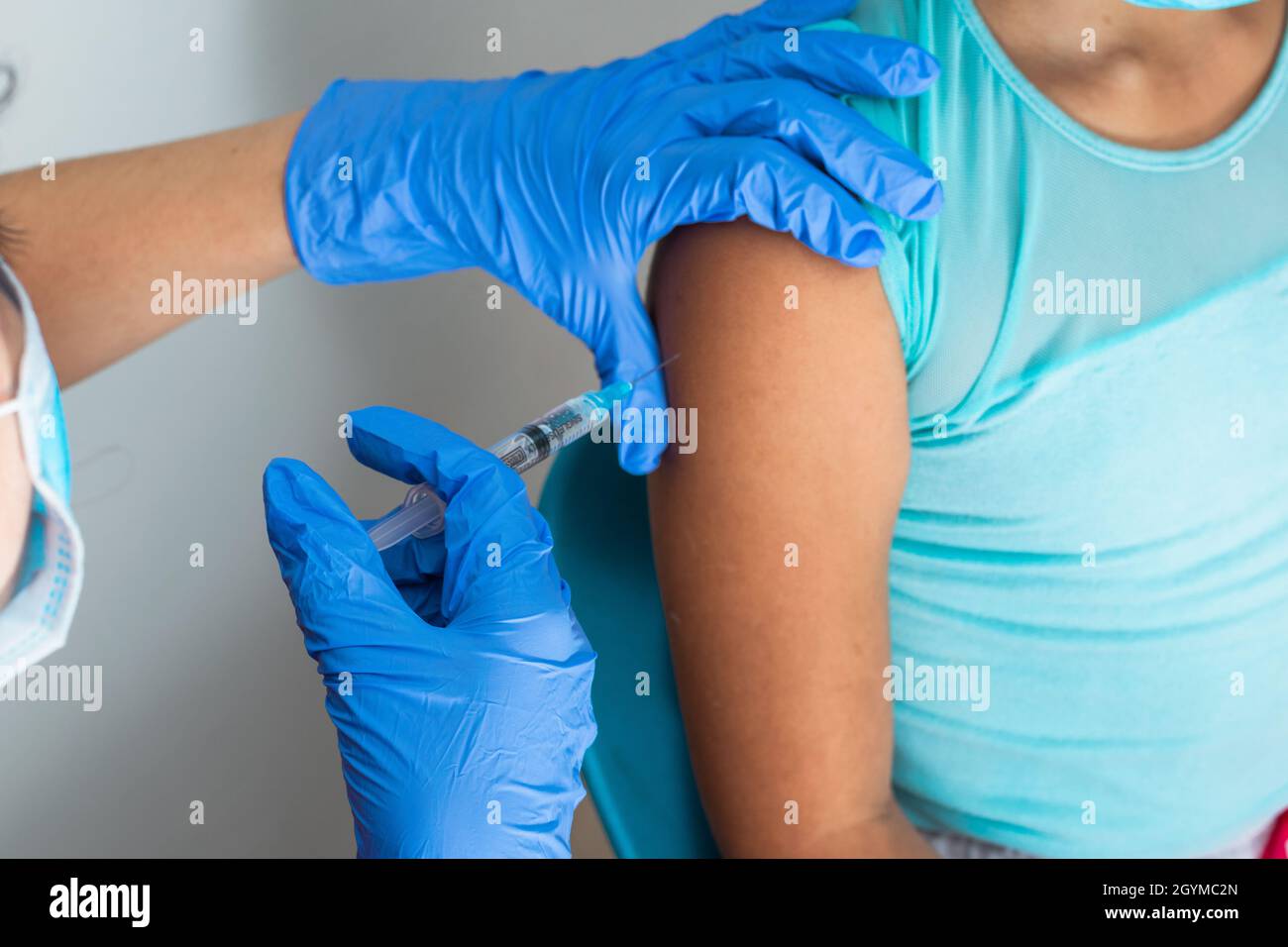 Kinderkrankenschwester Injektionsarm des braunen Mädchens. Arzt injiziert covid-19-Impfstoff. Krankenschwester entfernt Spritze vom Arm, Grippe-Impfstoff. Medizinisches Konzept, Gesundheit Stockfoto