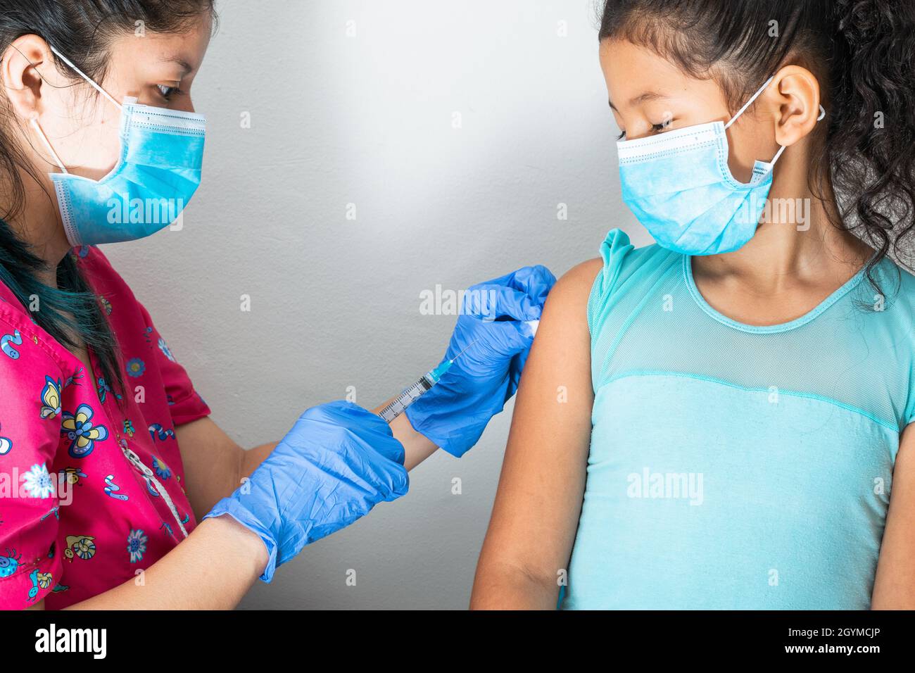 Kinderkrankenschwester Injektionsarm des braunen Mädchens. Arzt injiziert covid-19-Impfstoff. Krankenschwester entfernt Spritze vom Arm, Grippe-Impfstoff. Medizinisches Konzept, Gesundheit Stockfoto