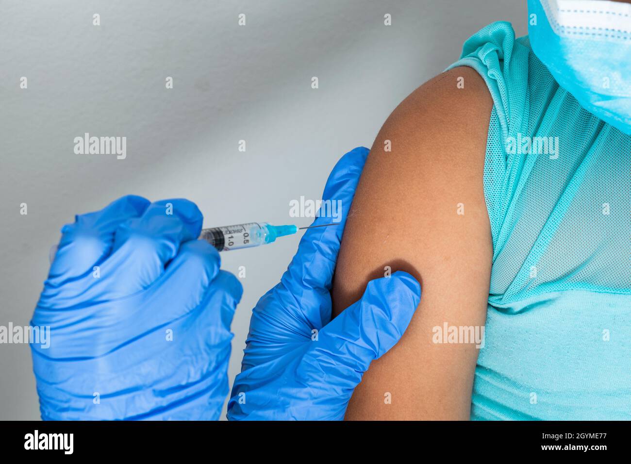 Kinderkrankenschwester im Begriff, die Injektion in den Arm eines kleinen braunen Mädchens zu verabreichen. Arzt injiziert covid-19-Impfstoff. Grippe-Impfstoff. Medizinisches Concep Stockfoto