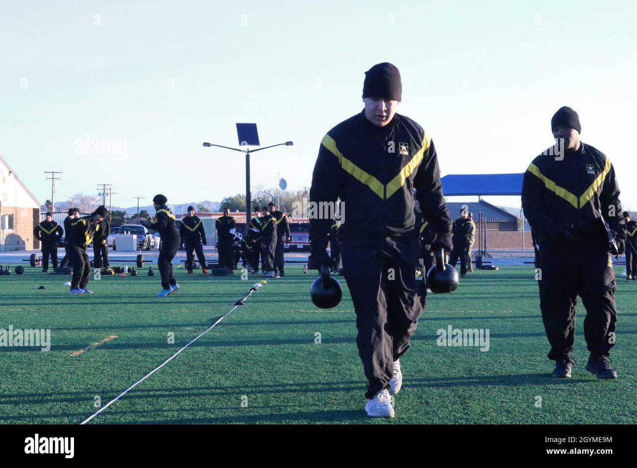 Ein Trooper trägt zwei 40-Pfund-Kettlebells bis zum Ende der 25-Meter-Bahn für den Trainingstest Army Combat Fitness auf dem Mehrzweckfeld, Fort Irwin, Kalifornien, am 31. Januar 2020. Die fünf Teile des Sprint-Drag-Carry sind, in der Reihenfolge, ein Sprint, Schlitten ziehen, seitliche Shuffle, kettlebell tragen, und ein weiterer Sprint. Stockfoto