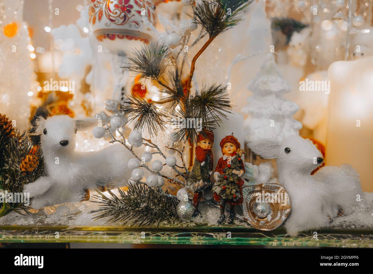 Weiße Spielzeugkitze und Christbaumzweig mit silbernem Glitzer auf einer festlichen Schaufensterfront. Neujahr und frohe Weihnachtsdekorationen und ein magischer Winter Stockfoto