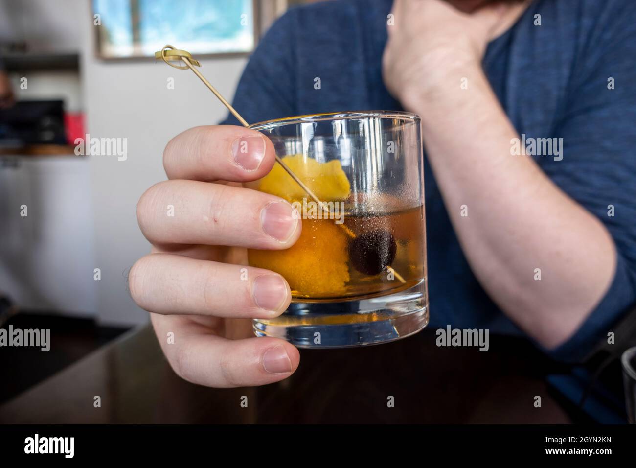 Nahaufnahme einer kauskasischen männlichen Hand, die ein altmodisches alkoholisches Getränk in einer Bar und einem Restaurant hält Stockfoto